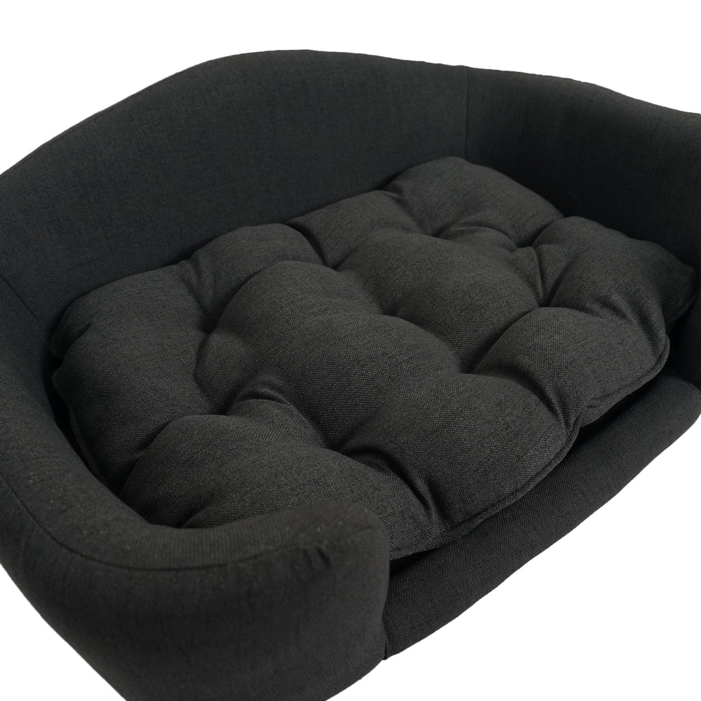 Black pet bed with tufted cushion on a white background