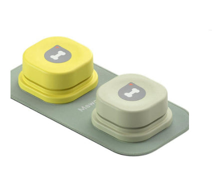Two small, round, yellow and beige dog waste bags with a gray logo on a green tray against a white background.