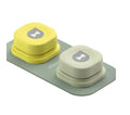 Two small, round, yellow and beige dog waste bags with a gray logo on a green tray against a white background.