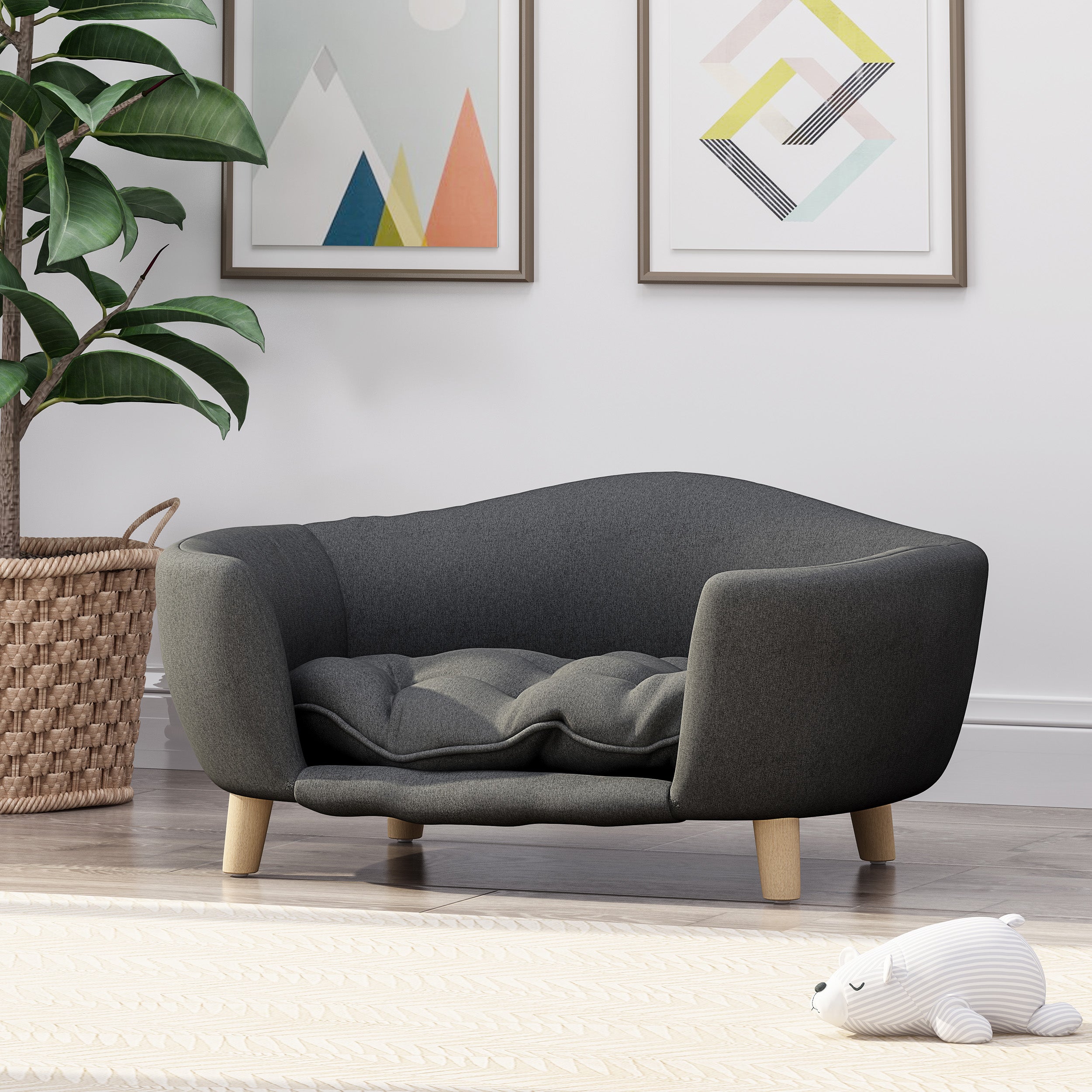Modern gray pet bed with wooden legs in a room with a plant and abstract art on the wall.